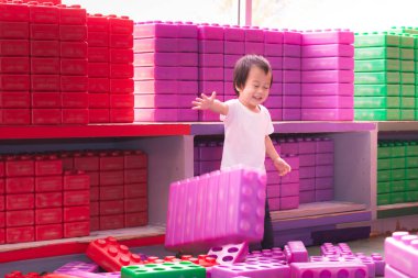 Asyalı çocuk oyuncakları yerden yere iterken eğleniyor, gözleri kapalı, çocuk öğreniyor, 2 yaşında bir çocuk. Mutlu evlat evde oyuncak bloklarıyla oynuyor..