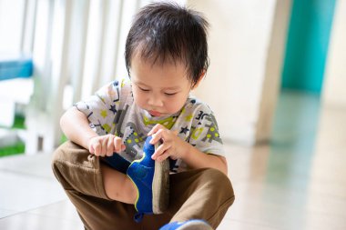 2 yaşında şirin bir çocuk dikkatle mavi spor ayakkabı giyiyor. Kişisel gelişim. Günlük rutin, erken çocukluk eğitimi.