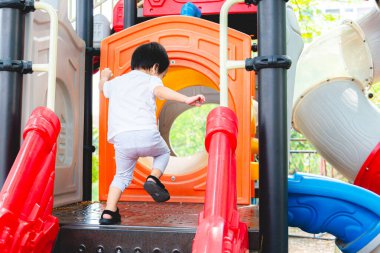 Küçük çocuk yaz parkında kayıyor ve oyun parkında mutlu bir şekilde oynuyor. 2 yaşında küçük bir oğlum var. Çocuğun arka plan görüntüsü.