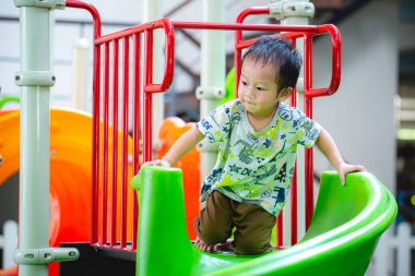 Küçük çocuk yazın açık havada oyun parkında mutlu mesut oynuyor. Çocuğun vücudu terle kaplıydı..