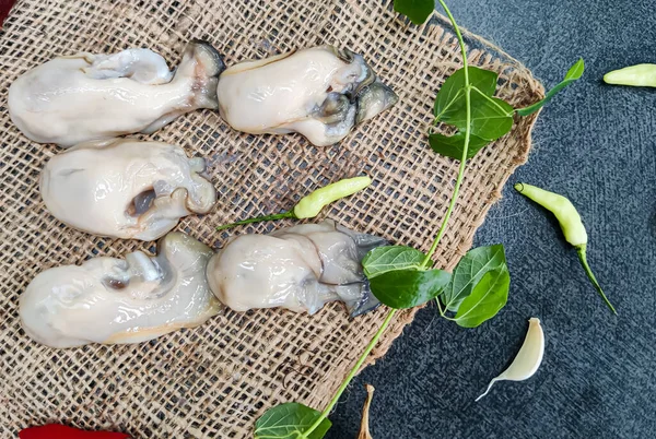 Mutfak arka planında sebzelerle süslenmiş taze istiridyelerin seçici odağı.