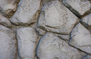 Görüntü büyük bloklardan yapılmış taş duvarları gösteriyor. Doku pürüzlü, çatlaklar ve düzensizliklerle, yüzeye doğal bir görünüm kazandırıyor..                        