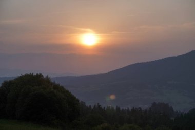 Dağlarda sisli gün batımı.