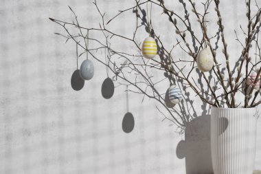 colorful eggs are on pussy twigs or branches willow. the easter decor on light background with copy space