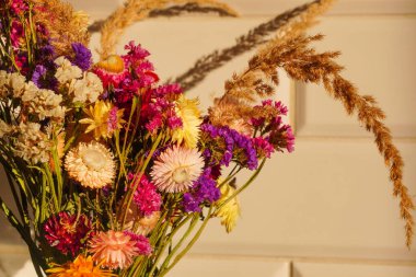 Yumuşak güneş ışığında çok renkli kurutulmuş çiçekler ve beyaz fayansların üzerinde bir gölge. Evin ya da dairenin dekorasyonu. Bir buket potpuri. Yüksek kalite fotoğraf
