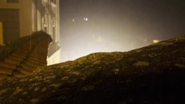 Geceleri binaların ve lambaların yanında şiddetli yağmur yağar. Işık altında görülebilen su damlaları