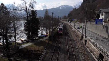 16 Nisan 2025 - Zell am See, Autria, Train dağların arka planına gidiyor. Halka açık bir yer. OBB ana demiryolu hattı