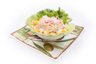 Yumurtalı pirinç salatası, mısır, yengeç çubuğu ve marul yaprağı şeklinde bir tabakta peçete.