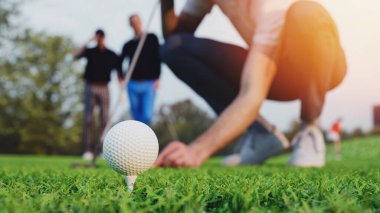 Adamın biri golf sahasındaki golf sahasına golf topu koyuyor. Sağ elinde golf sopası var. Sol eli golf topunu golf sahasına koyuyor. 3d, görüntüleme, illüstrasyon,