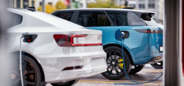 Şehirdeki bir kamu şarj istasyonuna takılan modern elektrikli araçlar, sürdürülebilir taşımacılığa geçişi vurguluyor