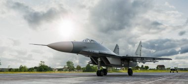 Bulutlu gökyüzünün altında güneş ışığıyla parlayan modern bir savaş uçağının 3 boyutlu görüntüsü.