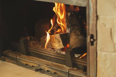 Kışın odun sobasıyla ısıtma evi. Köy odasındaki şöminede odun yakmak. Gaz ve elektriğe alternatif olarak şömine ısıtma