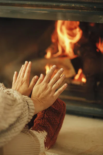 穿着舒适毛袜的女人在乡村房间的壁炉边热身 手热脚 冬天用烧木柴的炉灶取暖 年轻时尚的女性坐在农舍的壁炉前 — 图库照片