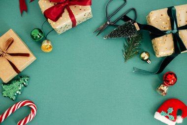 Modern noel yatağı. Şık paketlenmiş Noel hediyeleri ve yeşil arka planda şenlikli çerçeve kompozisyonu. Mutlu Noeller ve mutlu tatiller. Kış tatili afişi, kopyalama alanı