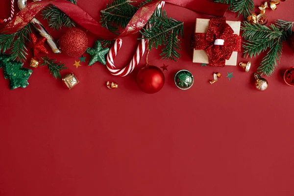 メリークリスマス モダンクリスマスフラットレイ 赤い背景にスタイリッシュなクリスマスの贈り物 赤ちゃん モミの枝 コンフェッティとキャンディーの杖 季節グリーティングカードテンプレート テキストのためのスペース 冬休み — ストック写真