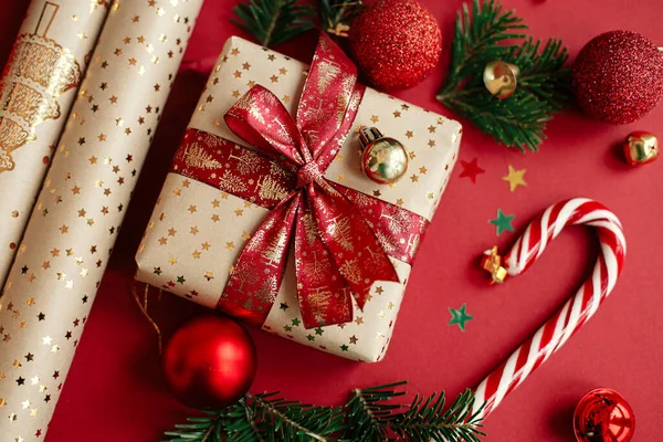現代のクリスマスのフラットレイアウト 赤い背景にスタイリッシュなクリスマスの贈り物 包装紙 モミの枝 キャンディー杖と赤ちゃんの組成物 メリークリスマスとハッピーホリデー 祭りの旗 — ストック写真