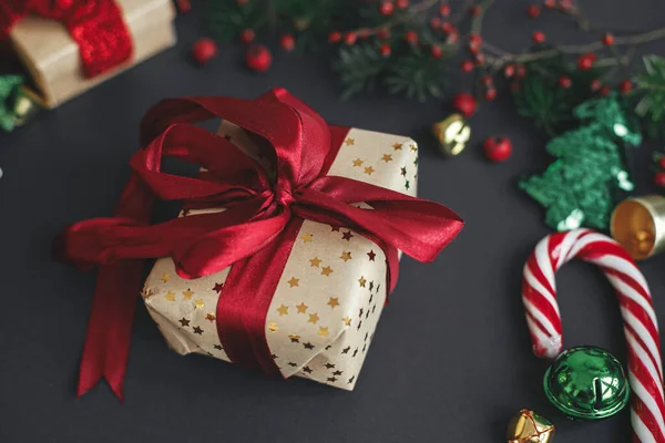 メリークリスマスとハッピーホリデー スタイリッシュなクリスマスギフトや枝 赤い果実 黒い背景の金の装飾 シーズンのグリーティングカード 冬の休日 現代のお祝いのバナー — ストック写真