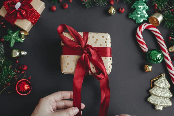 Hands Wrapping Stijlvolle Kerstcadeau Met Rood Lint Zwarte Achtergrond Met — Stockfoto