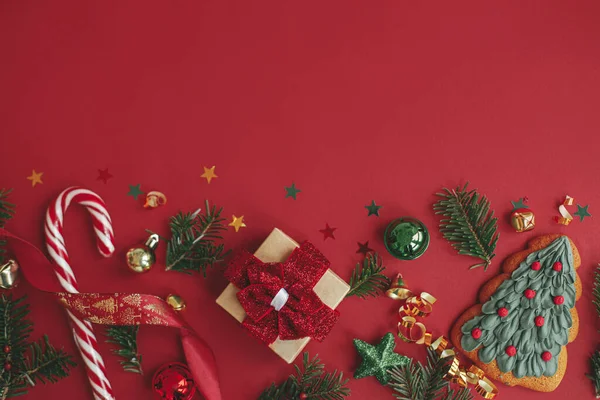 メリークリスマス モダンクリスマスフラットレイ 赤い背景にスタイリッシュなクリスマスの贈り物 赤ちゃん モミの枝 コンフェッティとキャンディーの杖 季節グリーティングカードテンプレート テキストのためのスペース 冬休み ロイヤリティフリーのストック写真