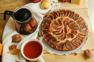 Tarçınlı taze pişmiş elmalı turta, sonbahar yaprakları, balkabakları ve fındıklı sıcak çay. Hygge evde, sıcak bir sonbahar günü..