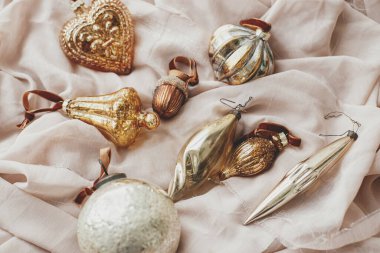 Mutlu Noeller! Yumuşak pastel kumaş üzerinde şık Noel süslemeleri. Kış tatili hazırlıkları ve Noel ağacını altın mücevherlerle süslemek. Noel estetik afişi