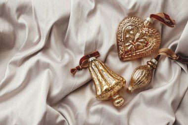 Şık bir Noel dairesi yumuşak pastel kumaş üzerine eski püskü süsler serilmiş. Mutlu Noeller! Altın takılarla tatil hazırlığı. Noel estetik afişi. Metin için boşluk