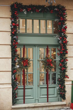 Süslü noel köknar dalları kırmızı takılar ve dış yüzeyinde fiyonk olan çelenkler. Şehir caddesinde modern noel dekorasyonu. Avrupa 'da kış tatili. Mutlu Noeller.