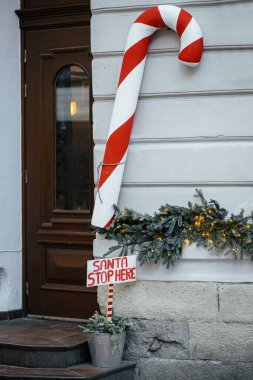 Büyük şeker kamışları yapın ve Noel Baba 'nın burada, dış binada durduğunu belirtin. Şehir caddesinde modern noel dekorasyonu. Avrupa 'da kış tatili. Şenlikli dekorasyonlar