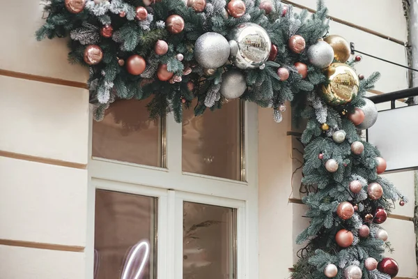 圣诞枞树枝条上的花柱粉红的灌木布置在建筑物外部的窗上 现代圣诞节装饰在城市街道上 欧洲寒假 节日装饰 — 图库照片