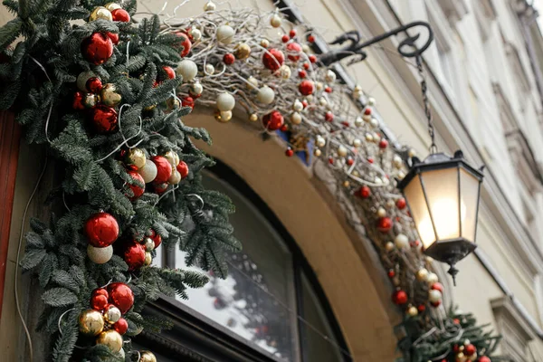 提灯付きの古いドアのスタイリッシュなクリスマスレッドとゴールドのベーブルや枝 街の通りで近代的なクリスマスの装飾 ヨーロッパでの冬の休暇 メリークリスマスとハッピーホリデー — ストック写真