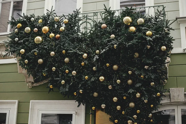 緑と金の泡と建物の外観上の照明とスタイリッシュなクリスマスモミの枝 街の通りで近代的なクリスマスの装飾 ヨーロッパでの冬の休暇 メリークリスマス — ストック写真