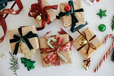 Şık Noel hediyeleri düzdü. Modern ambalajlı Noel hediye kutuları, altın kağıt, kırmızı ve yeşil kurdeleler, beyaz ahşap süslemeler. Mutlu Noeller ve mutlu tatiller! Bayram bayrağı