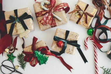 Mutlu Noeller ve mutlu tatiller! Şık Noel hediyeleri düzdü. Modern ambalajlı Noel hediye kutuları, altın kağıt, kırmızı ve yeşil kurdeleler, beyaz ahşap süslemeler. Bayram bayrağı