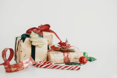 Mutlu Noeller ve mutlu tatiller! Modern ambalajlı Noel hediye kutuları, altın kağıt, kırmızı ve yeşil kurdeleler, beyaz ahşap süslemeler. Şık Noel hediyeleri. Atmosferik bayrak