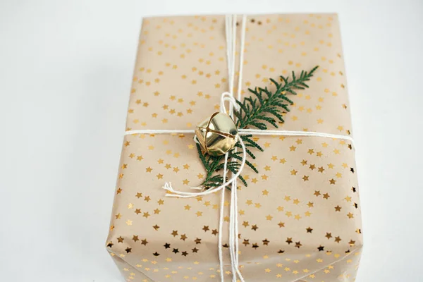 メリークリスマスとハッピーホリデー スタイリッシュなクリスマスプレゼント モミの枝 黄金の鐘とコピースペースと白い木の上のお祝いの紙の組成物と現代のクリスマスのギフトボックス — ストック写真