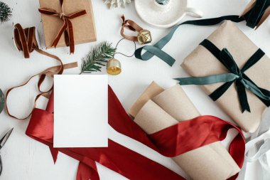 Christmas card mockup. Empty greeting card flat lay with christmas gift, decorations, ribbons, ornaments on white rustic table. Postcard template with space for text. Happy Holidays!