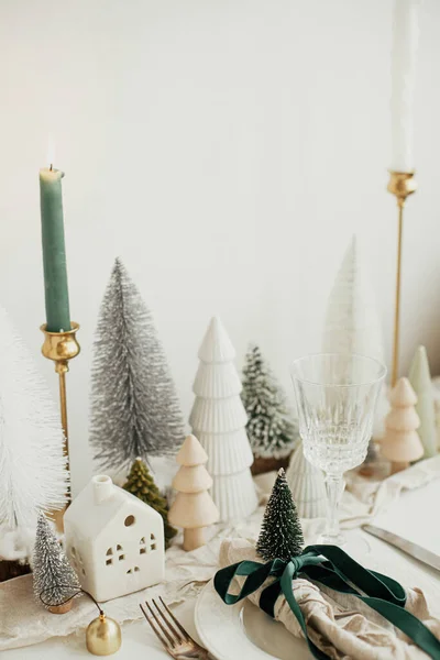 クリスマステーブルのセッティング プレート上のリボンと鐘を持つスタイリッシュなナプキン ヴィンテージのカトラリー モダンなお祝いのクリスマスツリーや白素朴なテーブルの上の家 テーブルの休日の配置 — ストック写真