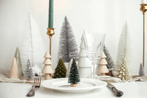 スタイリッシュなクリスマステーブルの設定 プレート上の近代的な小さなクリスマスツリー ヴィンテージのカトラリー ワイングラス モダンなクリスマスツリーや白素朴なテーブルの上の家 休日のブランチ 新年のお祝い — ストック写真