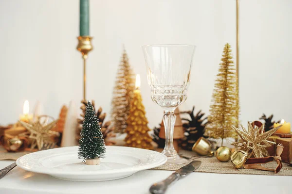 スタイリッシュなクリスマステーブルの設定 皿の上の小さなクリスマスツリー ヴィンテージのカトラリー ワイングラス 現代の黄金のクリスマスツリーとテーブルの上のキャンドル 休日のブランチ 新年のお祝い — ストック写真