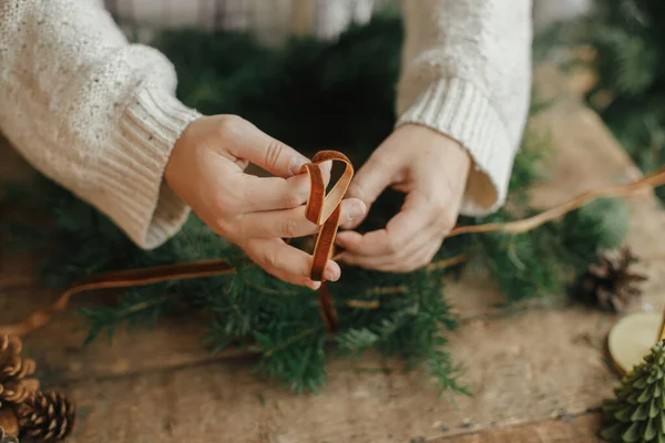 Samičí Ruce Držící Sametovou Stuhu Zdobící Vánoční Věnec Venkovském Dřevěném — Stock fotografie