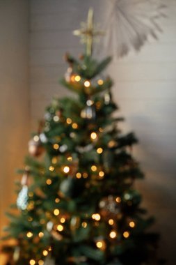 Bulanık ışıklandırılmış Noel ağacı. Soyut bulanık noel ağacı ve akşam odasında altın ışıklar. Atmosferik Noel görüntüsü, büyülü kış zamanı