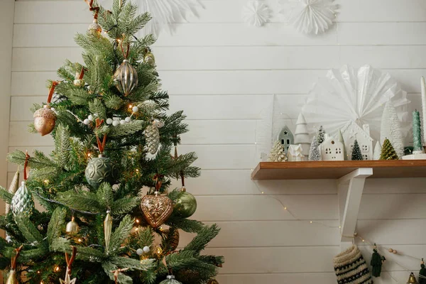 ヴィンテージの泡と小さなクリスマスの村の装飾とクリスマスツリー 現代のクリスマスツリーやお祝いの装飾された部屋でスタイリッシュな小さな木や家のシーン 大気の冬の休日 — ストック写真