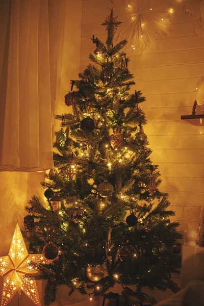 圣诞树在晚上的房间里闪烁着金色的灯光 现代装饰圣诞树与复古灌木在节日装饰房间与灯在前夜 大气时间 — 图库照片
