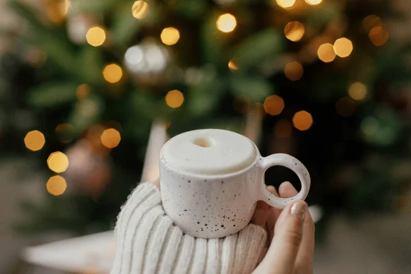 대기의 커피를 크리스마스 트리를 배경으로 있습니다 스웨터를 햇살을 받으며 여자들 — 스톡 사진