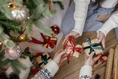 Noel ağacının altında, dekoratif odada Noel hediyelerini değiş tokuş eden eller. Mutlu Noeller ve mutlu tatiller! Zarif aile alışverişi, paketlenmiş hediyeler, eller yukarı görünüm