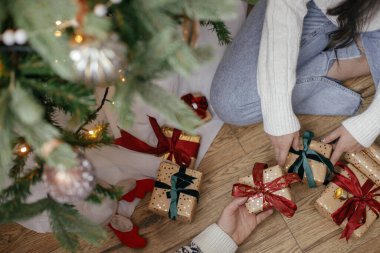 Noel ağacının altında, dekoratif odada Noel hediyelerini değiş tokuş eden eller. Mutlu Noeller ve mutlu tatiller! Zarif aile alışverişi, paketlenmiş hediyeler, eller yukarı görünüm