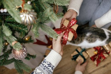 Noel ağacının altında, dekoratif odada Noel hediyelerini değiş tokuş eden eller. Mutlu Noeller ve mutlu tatiller! Zarif aile alışverişi, paketlenmiş hediyeler, eller yukarı görünüm