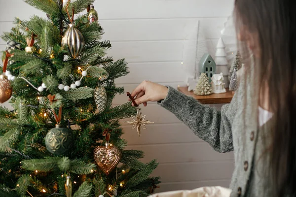在大气节日的房间里 用手装饰着有时尚色彩的圣诞树 圣诞快乐 准备寒假 穿着舒适毛衣的女人在树上挂上古董星 — 图库照片