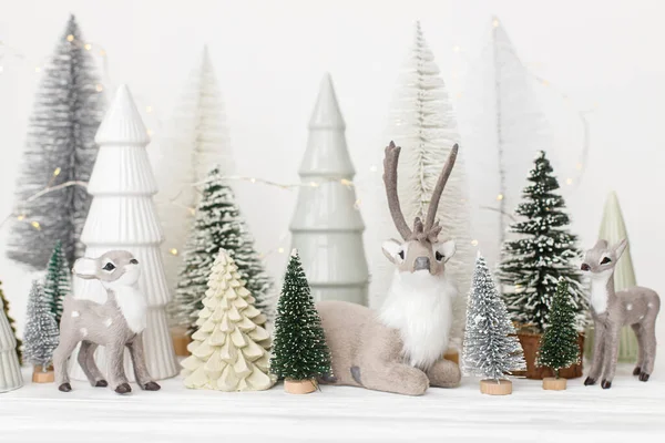 圣诞快乐 白色背景的别致的小圣诞树和驯鹿玩具 喜庆的圣诞场景 迷幻的雪地森林与鹿群 现代装饰 假日横幅 — 图库照片