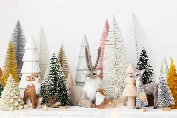 白い背景にスタイリッシュな小さなクリスマスツリーとトナカイのおもちゃ お祭りのクリスマスシーン かわいい鹿とミニチュアの雪の森 メリークリスマス モダンな装飾 休日のバナー — ストック写真